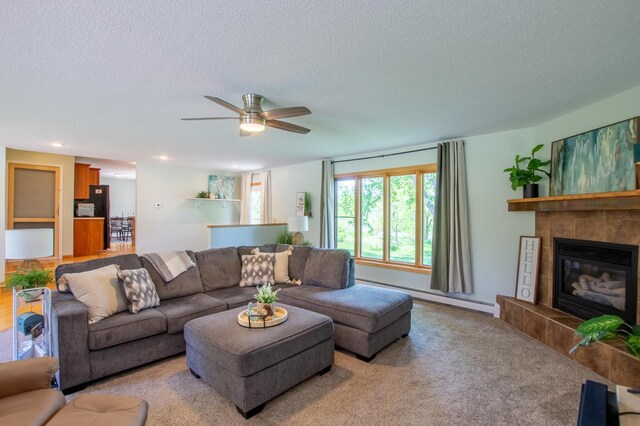 17367 Gull Lake Loop Rd NE, Bemidji, MN 56601 - living area with a baseboard heating unit, a textured ceiling, ceiling fan, a tiled fireplace, and carpet floors