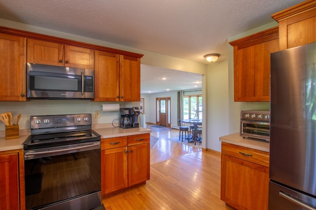 17367 Gull Lake Loop Rd NE, Bemidji, MN 56601 - kitchen featuring appliances with stainless steel finishes, brown cabinets, light countertops, recessed lighting, and a textured ceiling