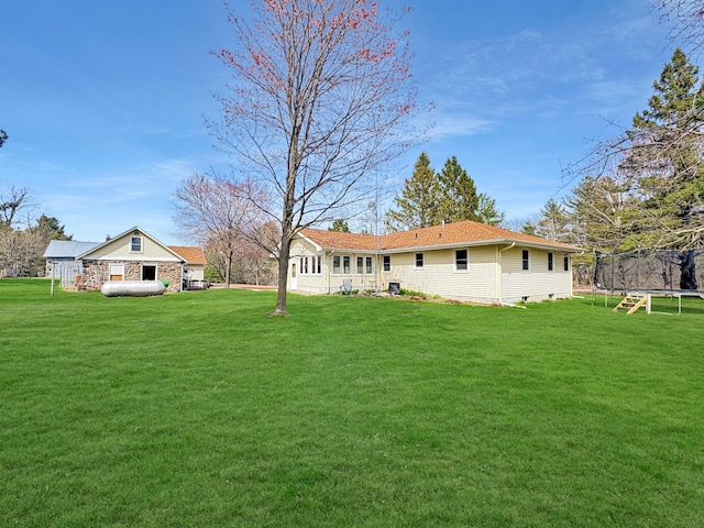 back of property with a yard and a trampoline
