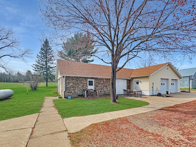 view of front of house featuring a detached garage, stone siding, a shingled roof, and a front yard