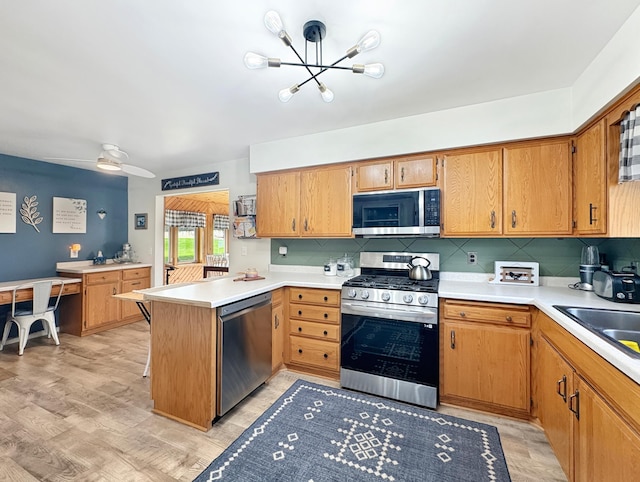 kitchen with light countertops, a peninsula, appliances with stainless steel finishes, and decorative backsplash