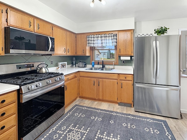 kitchen with light countertops, stainless steel appliances, a sink, and light wood-style flooring