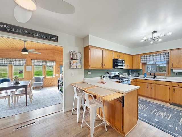 kitchen with appliances with stainless steel finishes, a sink, light countertops, backsplash, and visible vents