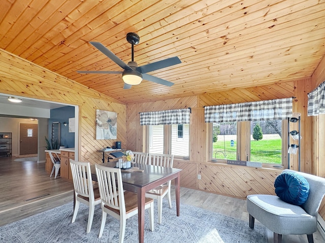 dining area with ceiling fan, wood walls, wooden ceiling, wood finished floors, and lofted ceiling