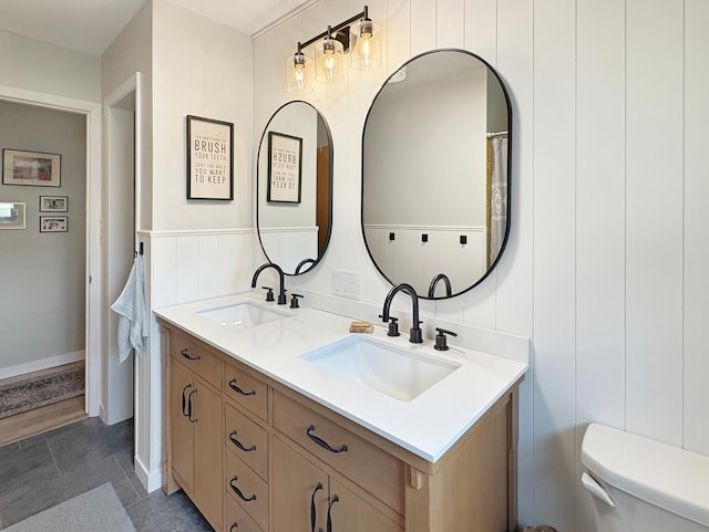 bathroom with a sink, toilet, and double vanity