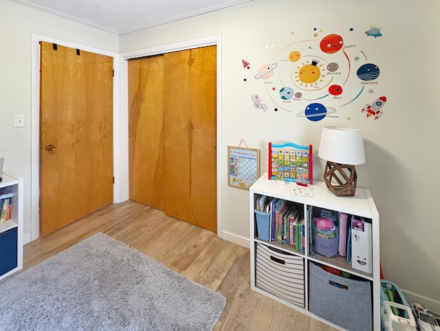 rec room with ornamental molding and wood finished floors