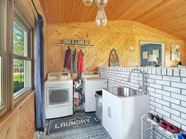 laundry area with laundry area, wooden walls, washer and clothes dryer, wood ceiling, and a sink