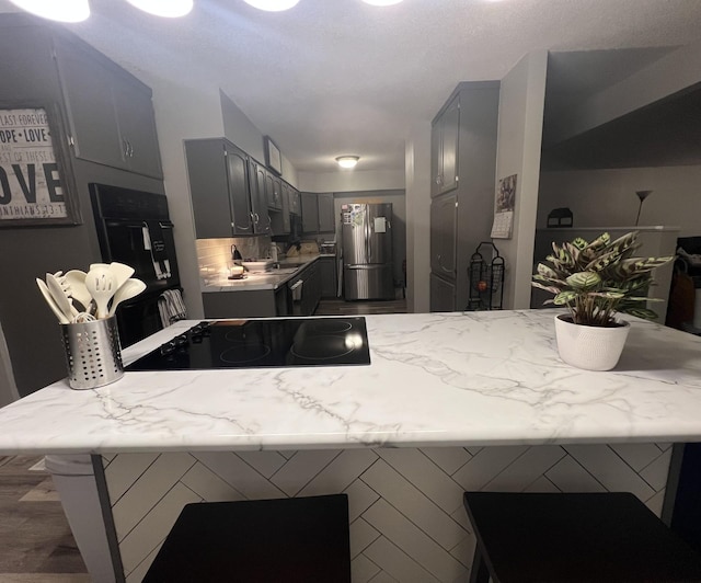 kitchen featuring freestanding refrigerator, light countertops, stove, and gray cabinets