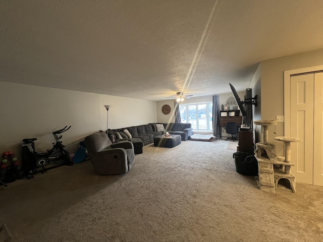living area featuring carpet flooring, ceiling fan, and a textured ceiling