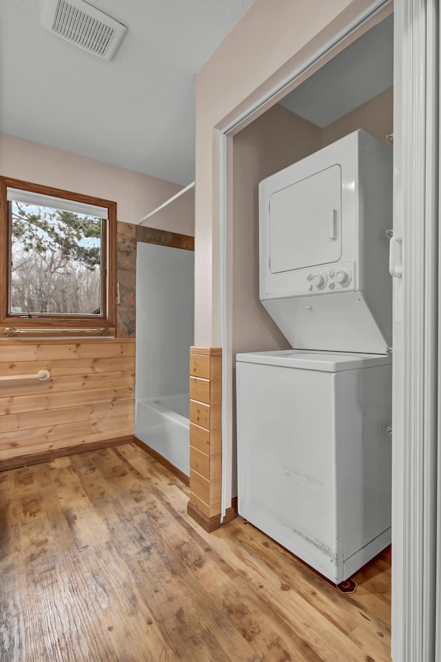 washroom with visible vents, stacked washer and clothes dryer, laundry area, and light wood finished floors