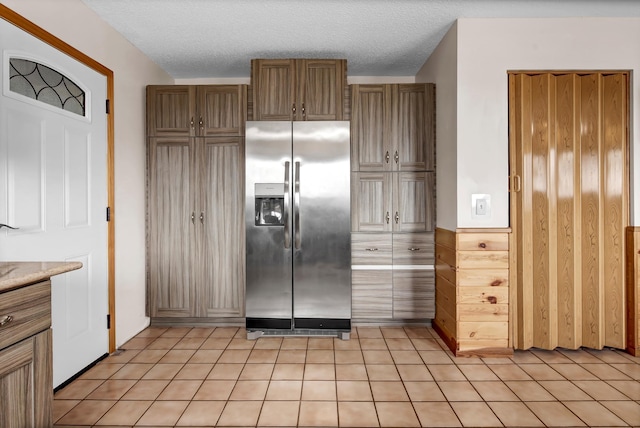 kitchen featuring light countertops, stainless steel fridge, a textured ceiling, and light tile patterned floors