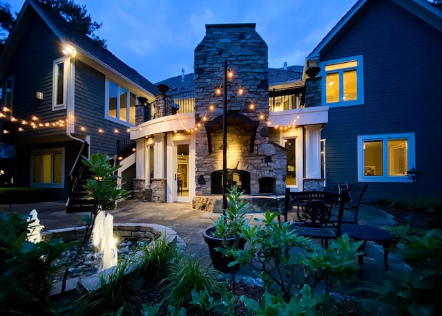 13980 Emerald Rdg, Minnetonka, MN 55305 - back of house with a fireplace, a balcony, a patio area, and stone siding