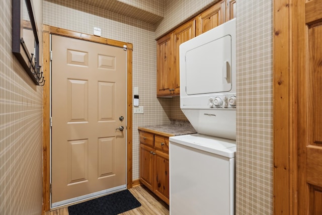 36306 Pine Bay Cir Unit 104, Crosslake, MN 56442 - washroom with estacked washer and dryer, wallpapered walls, cabinet space, and light wood-style flooring