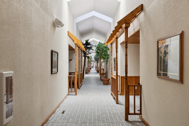36306 Pine Bay Cir Unit 104, Crosslake, MN 56442 - hallway with high vaulted ceiling, stairs, a textured wall, and wainscoting