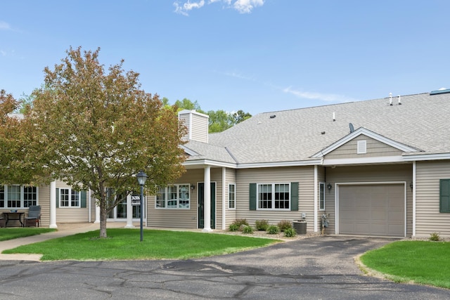 36306 Pine Bay Cir Unit 104, Crosslake, MN 56442 - view of front facade featuring a garage, asphalt driveway, a front lawn, central AC, and a shingled roof