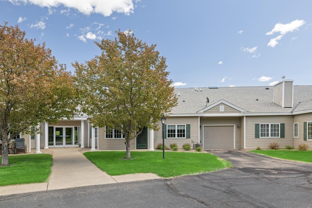 36306 Pine Bay Cir Unit 104, Crosslake, MN 56442 - view of front facade with an attached garage, driveway, a front lawn, a shingled roof, and a chimney