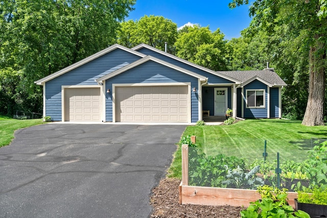 ranch-style home featuring an attached garage, aphalt driveway, a garden, and a front yard