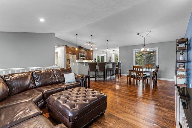living area with baseboards, vaulted ceiling, dark wood-style flooring, and a chandelier