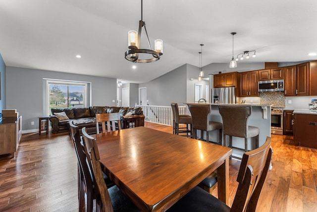 dining room featuring recessed lighting, a notable chandelier, lofted ceiling, and light wood-type flooring