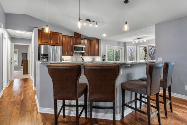 kitchen featuring appliances with stainless steel finishes, lofted ceiling, and a kitchen breakfast bar