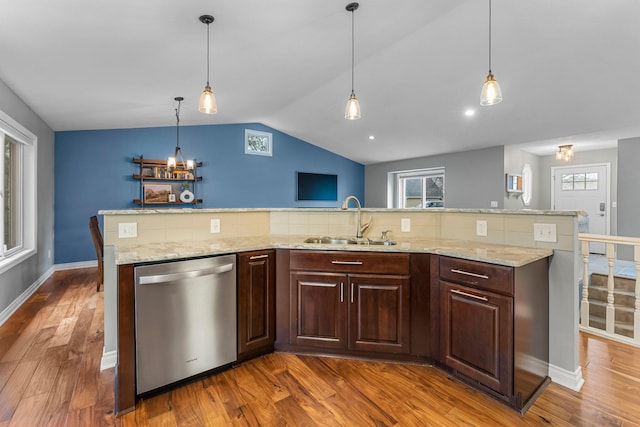 kitchen featuring stainless steel dishwasher, vaulted ceiling, light stone countertops, wood finished floors, and a sink