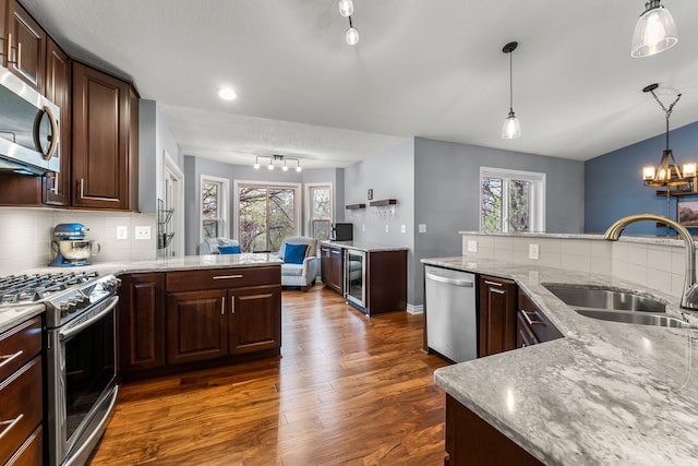 kitchen with dark wood-style floors, plenty of natural light, a sink, backsplash, and stainless steel appliances