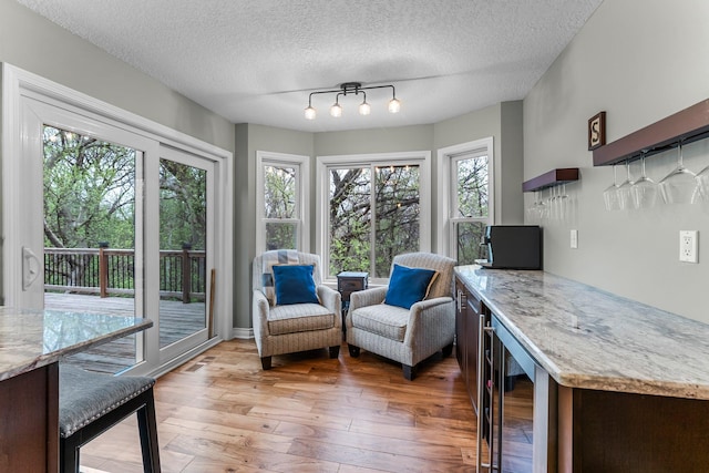 interior space featuring visible vents, wine cooler, light wood-style floors, a textured ceiling, and a dry bar