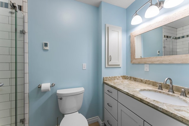 bathroom featuring vanity, baseboards, toilet, and tiled shower