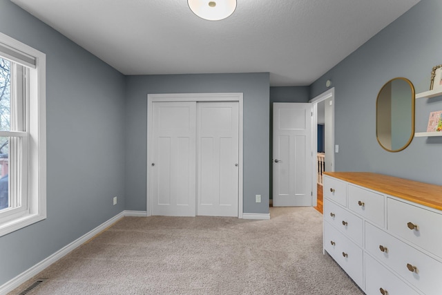 bedroom with a closet, baseboards, light colored carpet, and visible vents