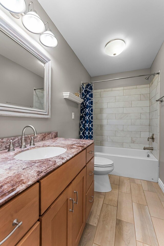 bathroom with vanity, wood finished floors, shower / bath combination with curtain, and toilet