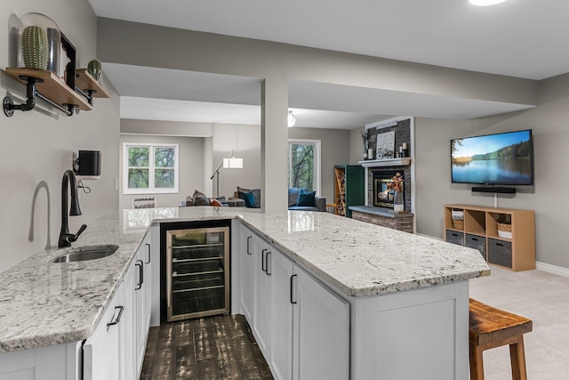 kitchen with a sink, light stone countertops, beverage cooler, and open floor plan