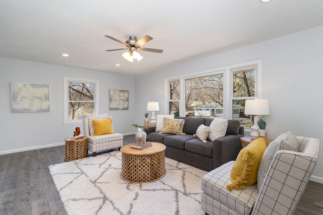 living room with ceiling fan, baseboards, and dark wood finished floors
