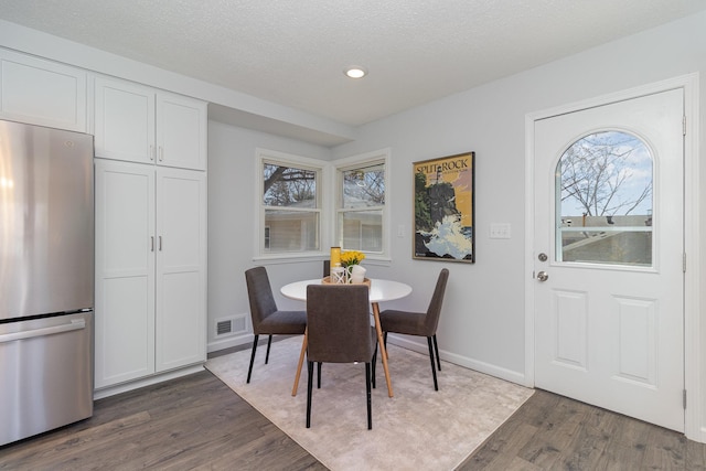 dining space with a textured ceiling, visible vents, recessed lighting, wood finished floors, and baseboards