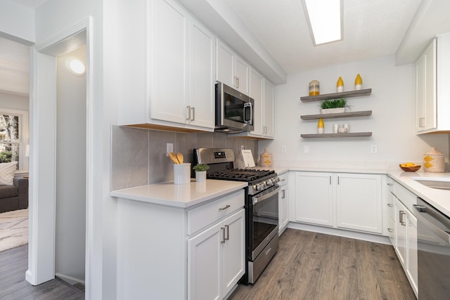 kitchen featuring open shelves, white cabinets, appliances with stainless steel finishes, wood finished floors, and light countertops