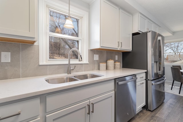 kitchen featuring white cabinetry, dishwasher, a sink, dark wood-style flooring, and backsplash