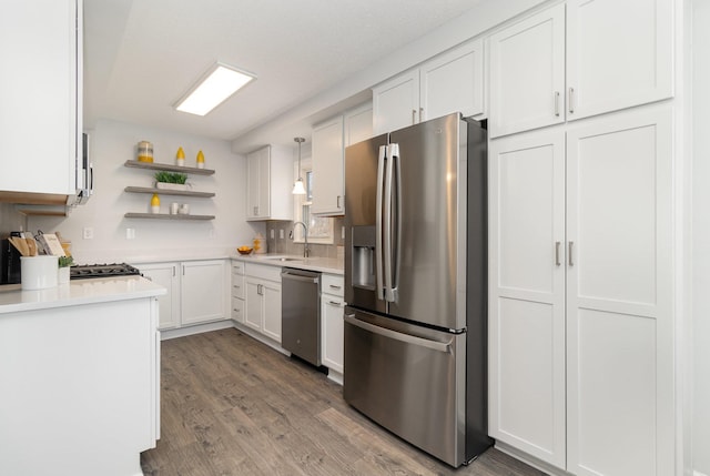 kitchen with white cabinetry, light countertops, open shelves, stainless steel appliances, and a sink