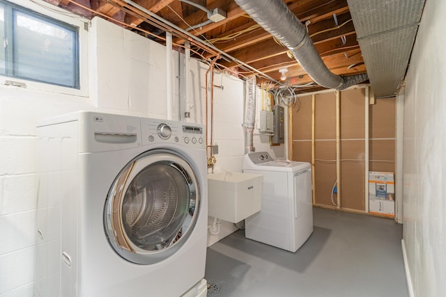 clothes washing area featuring electric panel, washing machine and dryer, laundry area, and a sink