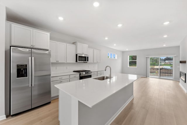 1543 Traverse Ln W, Saint Paul, MN 55118 - kitchen with stainless steel appliances, a sink, light wood-style flooring, a center island with sink, and backsplash