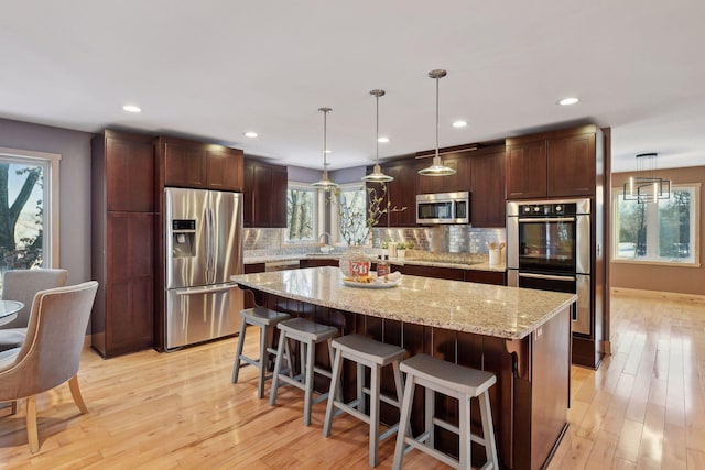 kitchen with a sink, a center island, decorative backsplash, and appliances with stainless steel finishes