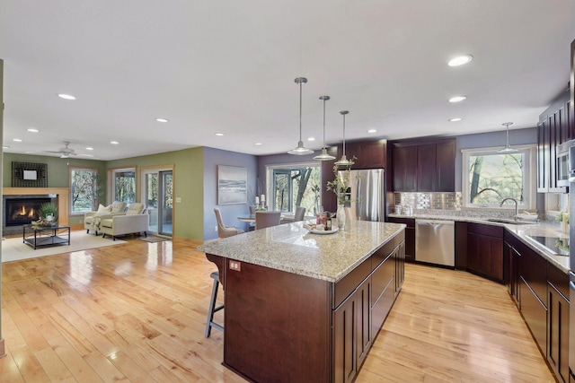 kitchen featuring hanging light fixtures, a sink, ceiling fan, appliances with stainless steel finishes, and light wood finished floors