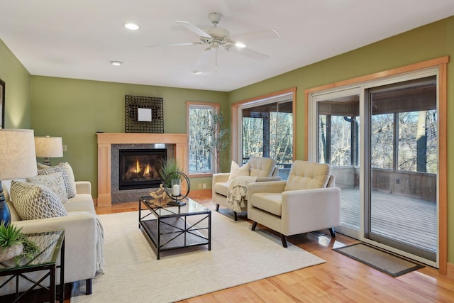 living room with wood finished floors, ceiling fan, a fireplace, and recessed lighting