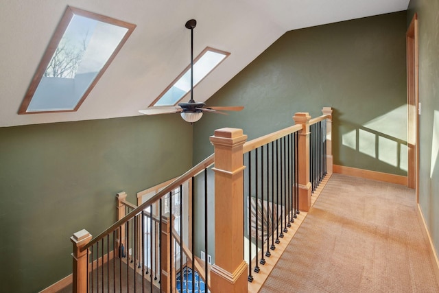 stairs featuring carpet, baseboards, a ceiling fan, and lofted ceiling with skylight