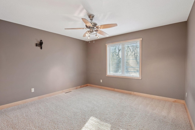 empty room with carpet flooring, baseboards, and a ceiling fan