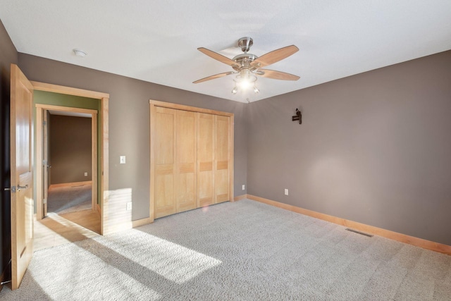 unfurnished bedroom with a closet, baseboards, a ceiling fan, visible vents, and carpet