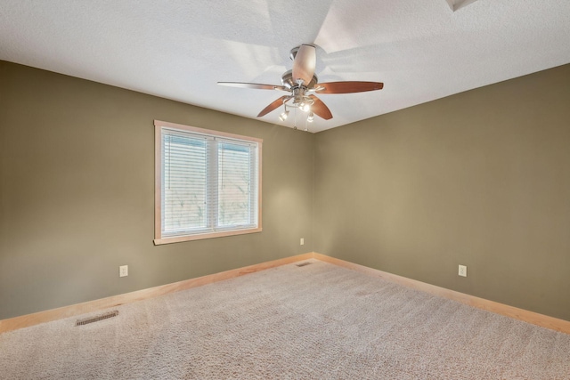 carpeted empty room with visible vents, baseboards, a ceiling fan, and a textured ceiling
