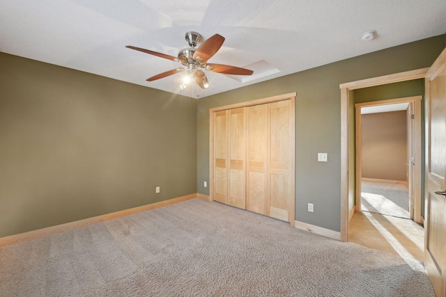 unfurnished bedroom with a closet, light colored carpet, baseboards, and a ceiling fan