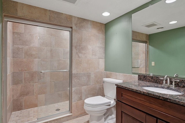 bathroom with vanity, a stall shower, toilet, visible vents, and tile walls