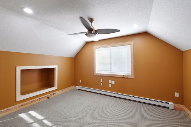 additional living space featuring vaulted ceiling, a textured ceiling, ceiling fan, carpet, and a baseboard radiator