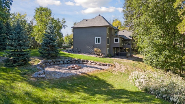 rear view of property featuring central air condition unit, a deck, a fire pit, and a lawn