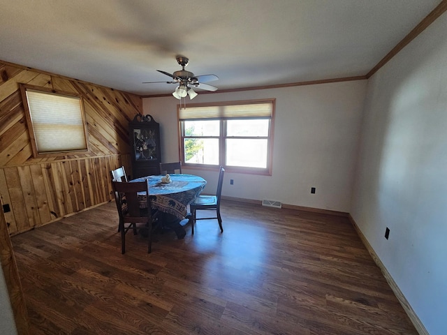 dining space featuring crown molding, a ceiling fan, wood walls, baseboards, and wood finished floors